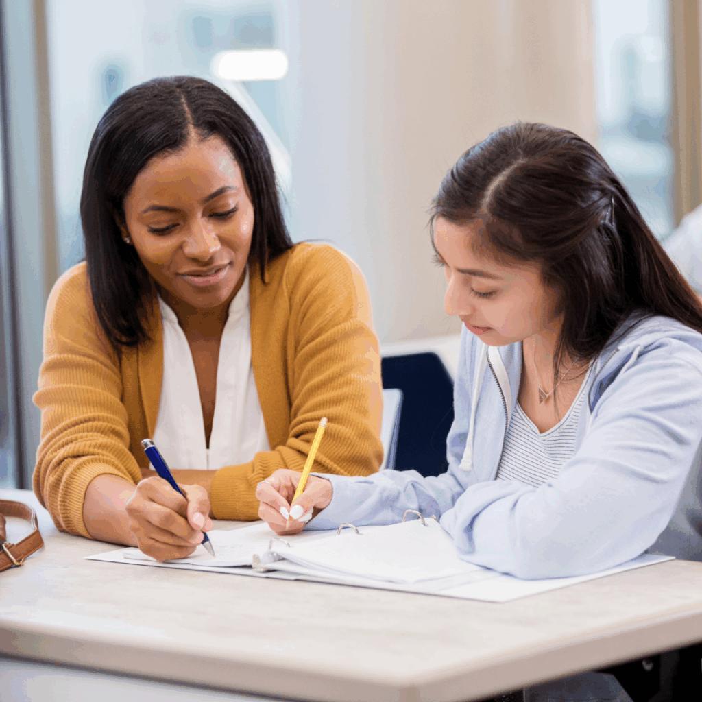 Coach et jeune en séance de coaching, assis à une table de travail